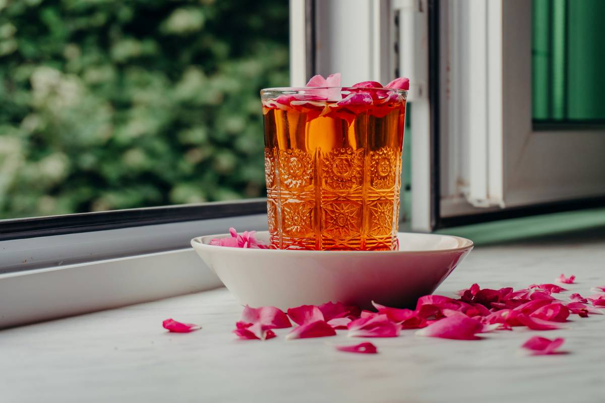 Fresh lemon balm leaves on a white ceramic plate beside a small mug of warm tea — lemon mood remedy solution